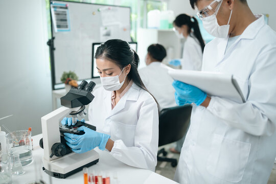 Laboratory microscope research scientists working in white lab coats conducting scientific analysis and testing biological samples for innovation in medical diagnostics and breakthroughs - Powered by Adobe