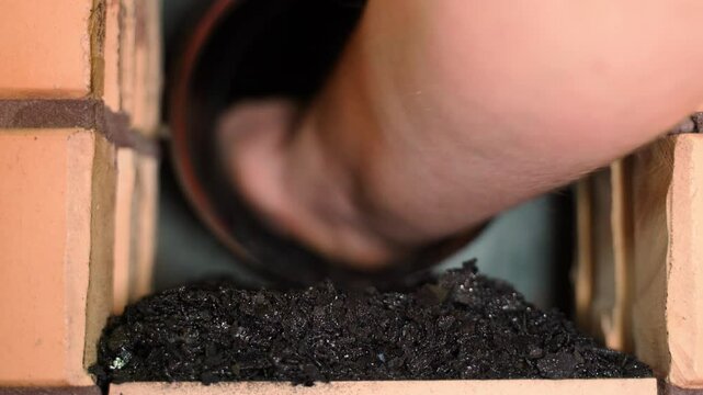 Raking soot out of a chimney by hand, close-up. Chimney maintenance and cleaning after the heating season