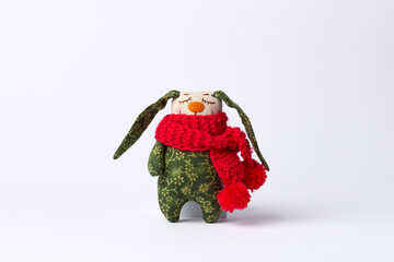 Handmade plush bunny with floppy ears wearing red knitted scarf and green floral fabric body design