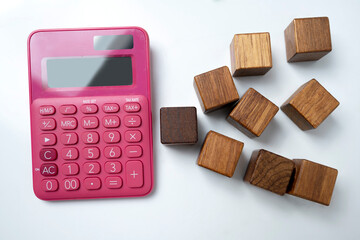 Top view of a pink calculator and wooden cubes on a white background. Mockup or Copy space. Concept...