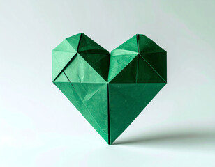 A green origami heart sculpture stands out against a light background, showcasing intricate folds and a unique geometric design