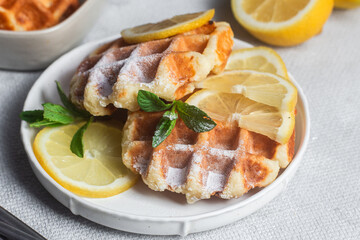 Belgian waffles made from cottage cheese with mint and lemon in a white plate on the table. Healthy breakfast