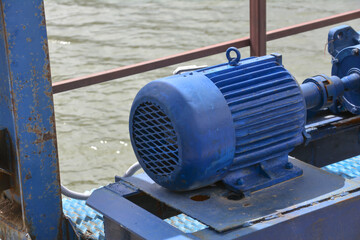 The blue motor of the water pump on the river, close-up. Water pump in a industrial building. Electric motor