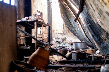 burned and damaged kitchen after a fire, showing scorched cookware, melted bottles, and blackened...
