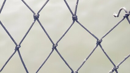 Fototapeta premium Close-up of a Textured Fishing Net with Sunlight Reflections on a Soft Water Surface in the Background
