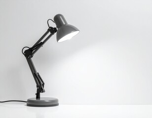 Gray articulated desk lamp illuminates white surface
