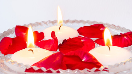 Bright macro of rose petals and lit candles in water. Decorative image for spa, relaxation or...