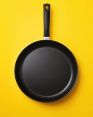Black frying pan isolated on yellow background top down view cooking utensil kitchenware cookware minimalist style studio shot