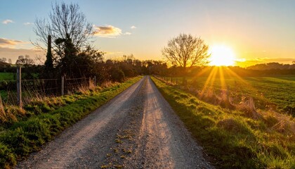 Obraz premium Serene Country Road at Sunset with Vibrant Sun Rays and Landscape