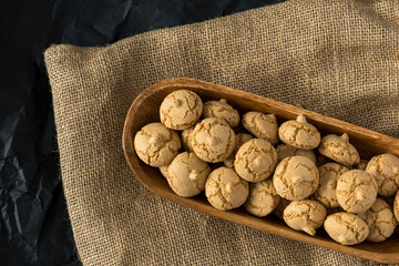 Amaretti cookie in a wooden bowl on a burlap background , top view , high-resolution . Delicious ,...