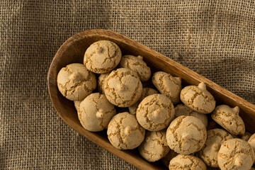 Amaretti cookie in a wooden bowl on a burlap background , top view , high-resolution . Delicious ,...
