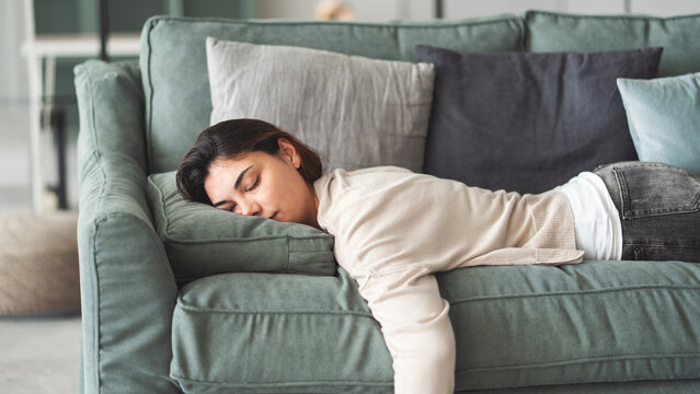 Exhausted young woman resting at home on couch