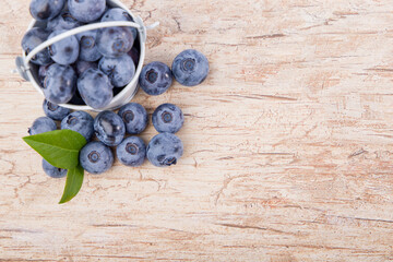 Fresh blueberries with leaves on wooden background. Top view with copy space