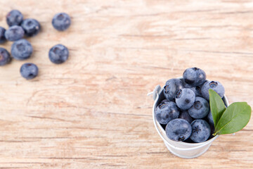 Fresh blueberries in a bucket on wooden background with copy space.