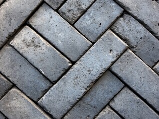 Close-up of a herringbone pattern made with gray concrete bricks, showcasing a textured and orderly paving design.