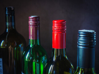 Close-up of metal cap on dark glass wine bottle, variety of wine bottles are lined up.