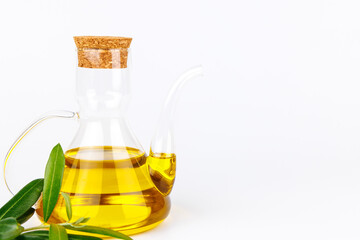 Glass olive oil jug with olive sprig in a clean white composition