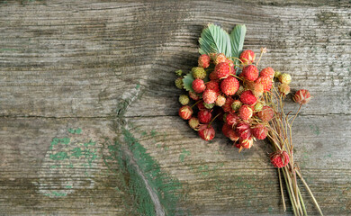 wild red strawberries on old wooden background. Fresh picking ripe sweet berries, natural organic...