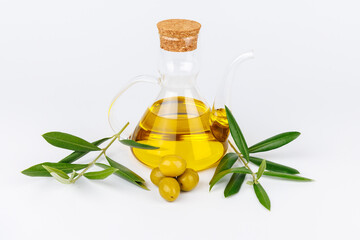 Glass oil cruet with green olives and olive branches on white background, Mediterranean culinary...