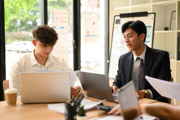 Obraz premium Team of Diverse Business People Discussing Reports in Modern Office