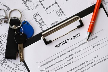 Pen and keys on Notice to quit form and planning blueprints of residential building project close up