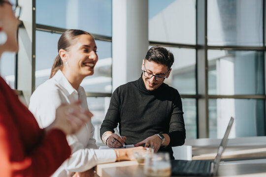 Business employees enjoying a collaborative discussion in a bright office kitchen environment. Professionals are engaged, smiling, and working together, fostering teamwork and communication in a
