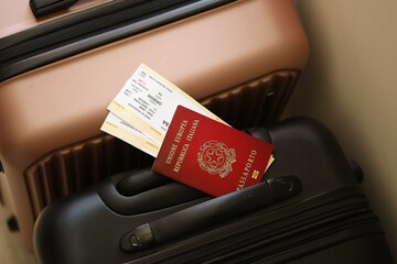 Italian passport with tickets lies on touristic suitcase close up in airport waiting hall