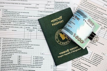 Bangladeshi taka money bills in big amount lies on table with passport and tax forms close up