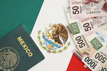 Mexican pesos money bills in big amount and passport lies on Mexico flag close up
