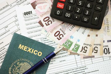Mexican pesos money bills in big amount lies on table with pen, calculator, passport and tax forms
