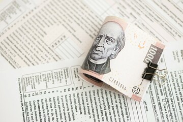 Mexican pesos money bills in big amount lies on table with tax forms close up