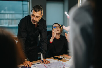 A diverse group of business colleagues engaged in a lively brainstorming session, analyzing ideas...