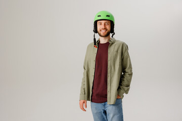 Fototapeta premium Young man dressed casually with a green helmet poses confidently in a studio setting while smiling