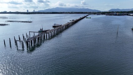 Long wooden pier stretching into a calm blue sea under a wide tropical sky, creating strong leading lines and a peaceful coastal atmosphere, ideal for travel, nature, and serene seascape concepts.