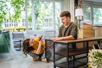 Adult couple use electric drill for assembling table at new apartment