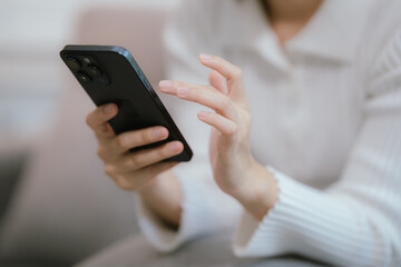 Close-up of a young woman's hand holding a smartphone and chatting on social media.