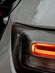 This is a detailed closeup shot of a cars tail light illuminated by rain droplets falling on its surface, creating a striking visual effect