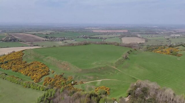An aerial receding view of the top and sides of the remains of the Iron Age Hillfort in rural Leicestershire, UK in springtime