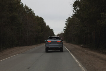 A car is currently driving down a winding road that winds its way through the dense woods and trees surrounding the area