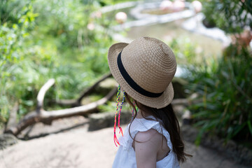 Lonely girl with multi-colored dreadlocks and a straw hat looks into the distance standing in the...