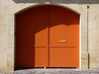 An old building with a bright orange gate after renovation.