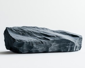 A large, textured black rock sits on a clean white surface, emphasizing its natural beauty and form