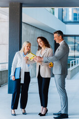 Businesspeople are discussing work while using a tablet and standing together in a modern office...