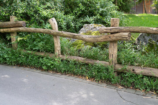 Old weather-worn wooden log fence in a summer rural area