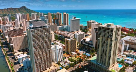 Flight around the high-rise building with solar panels on the top. Waterscape of the Pacific Ocean with boats and surfers on.
