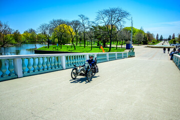 Naklejka premium Healthy active outdoor lifestyle: senior man hat sunglasses beard cycling on a recumbant tricycle on a bridge in sunshine on the Toronto Islands shot in spring room for text 