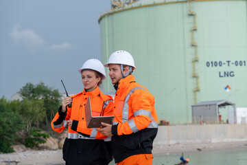 Workers communicate at an LNG facility during a project evaluation and safety check in daylight
