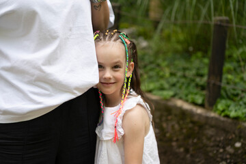 Mother hugging her smiling daughter in summer park. Concept of children's emotions and joy