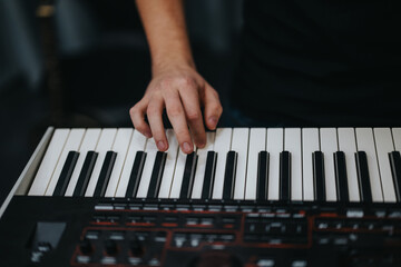 Obraz premium A musician's hand resting on a keyboard, creating music in a modern studio environment.