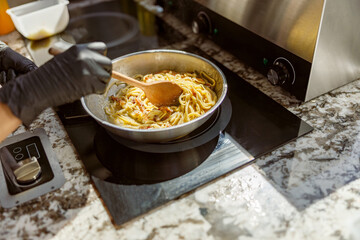 A talented chef diligently stirring freshly cooked pasta in a modern kitchen, beautifully showcasing the art of cooking
